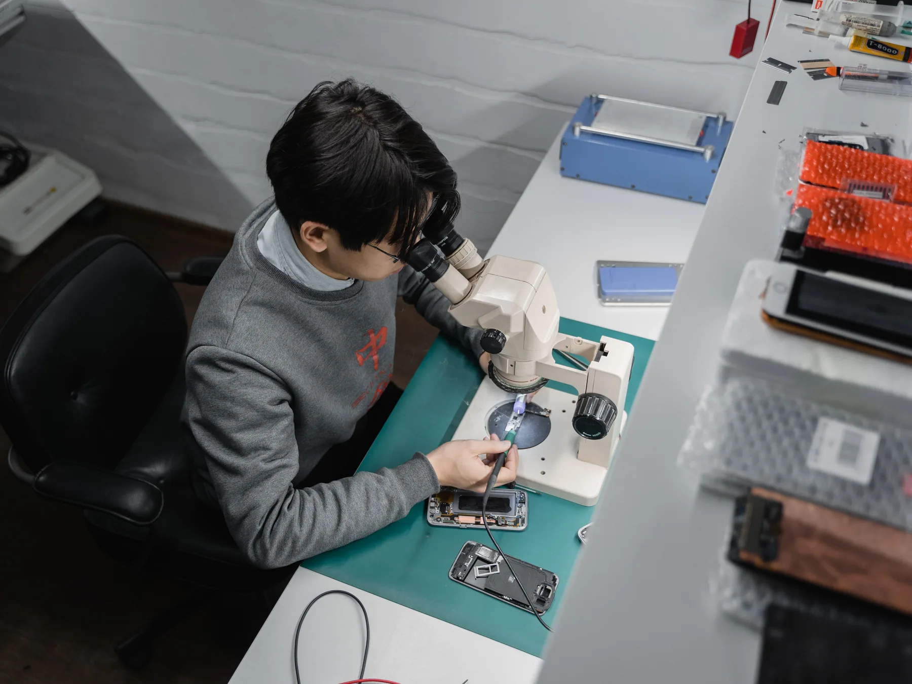 Technician examining a smartphone under a repair microscope