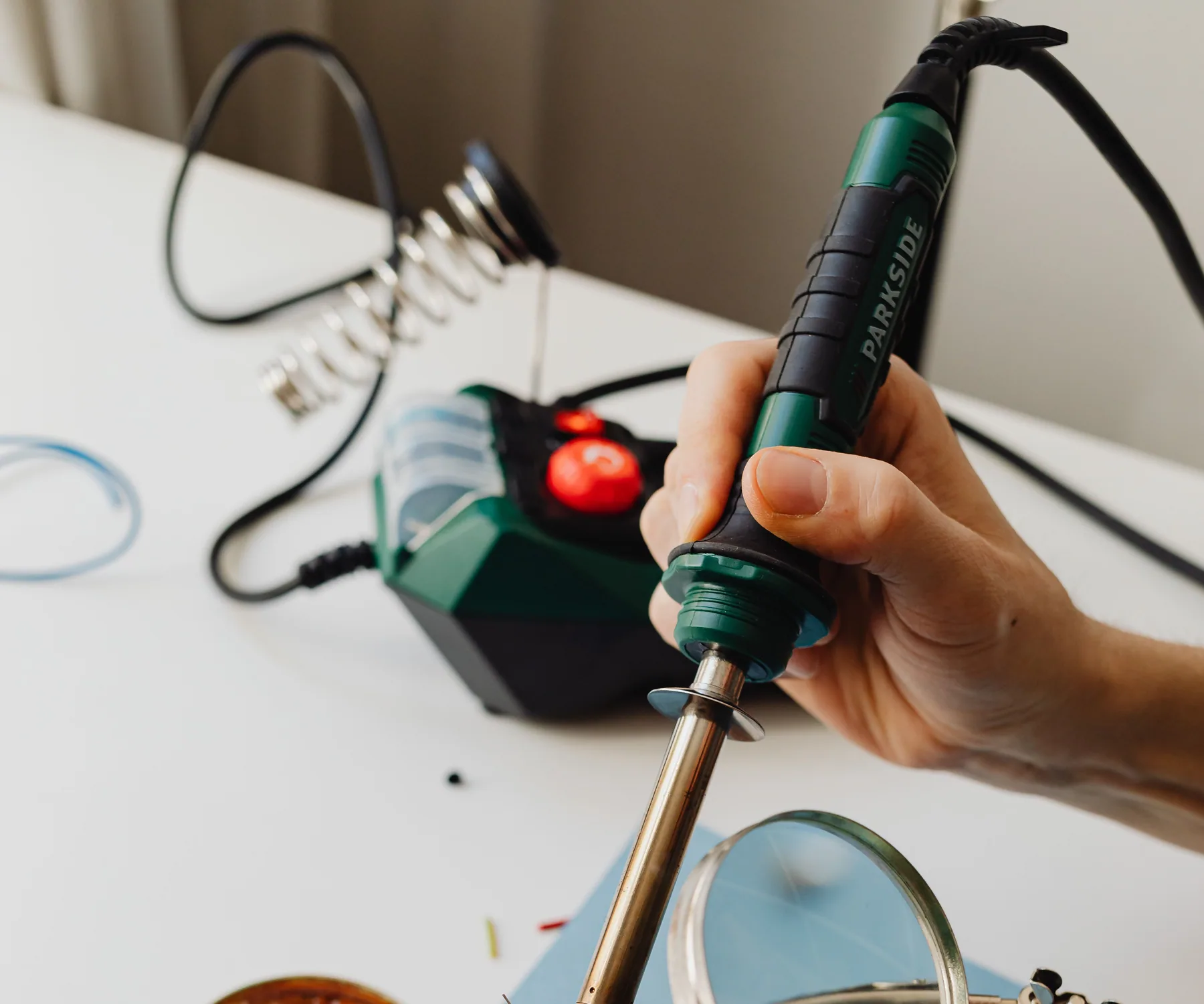 Hands performing precise soldering work on a circuit board